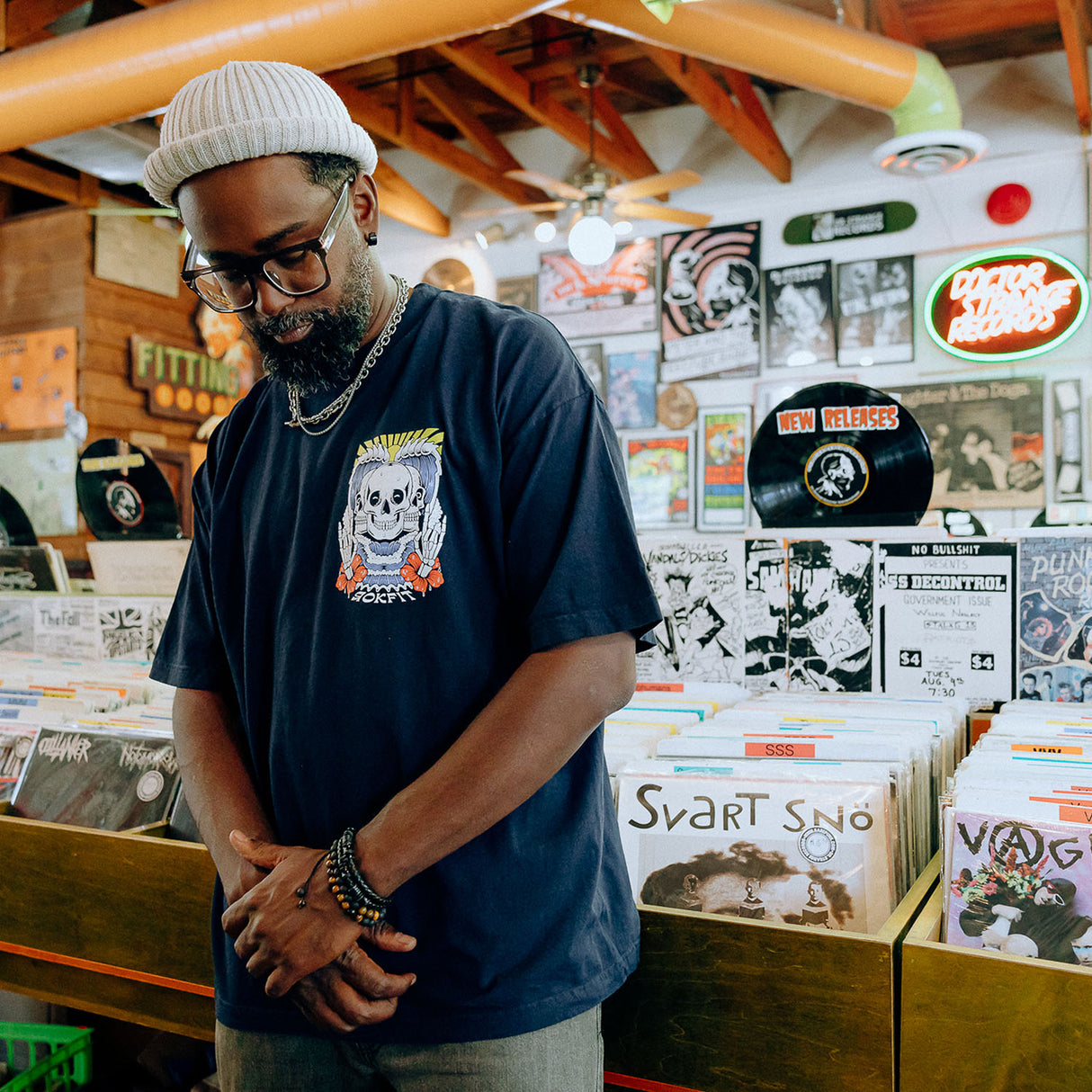 Male model in record store wearing unisex Street Tee with 'Discipline Weighs Ounces, Regret Weighs Tons' graphic
