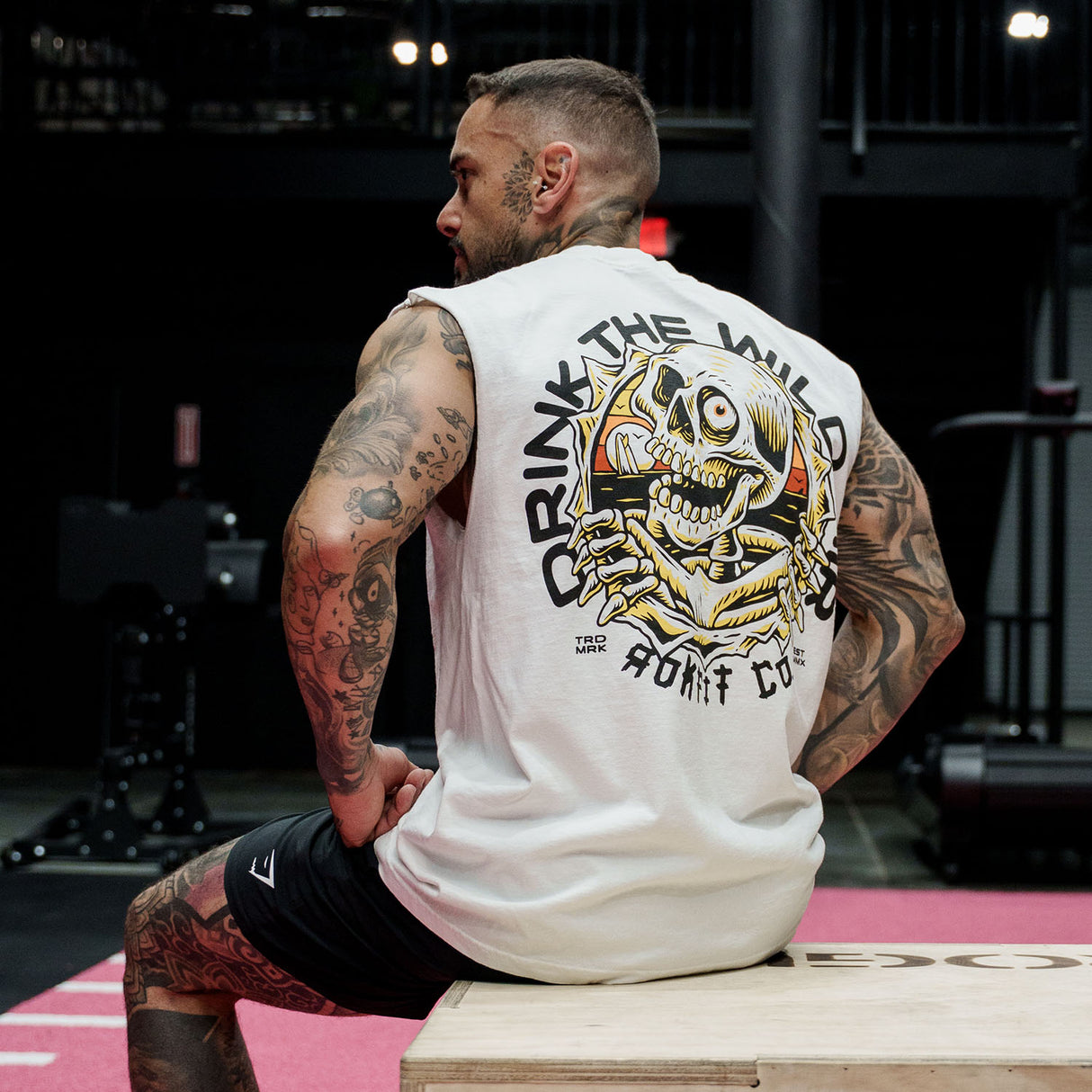 Male model in gym wearing a sleeveless street tee with 'Drink The Wild Air' graphic