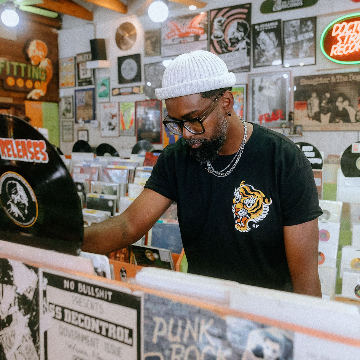 Male model in record store wearing unisex Active Tee with 'Make Excuses or Make Progress' graphic