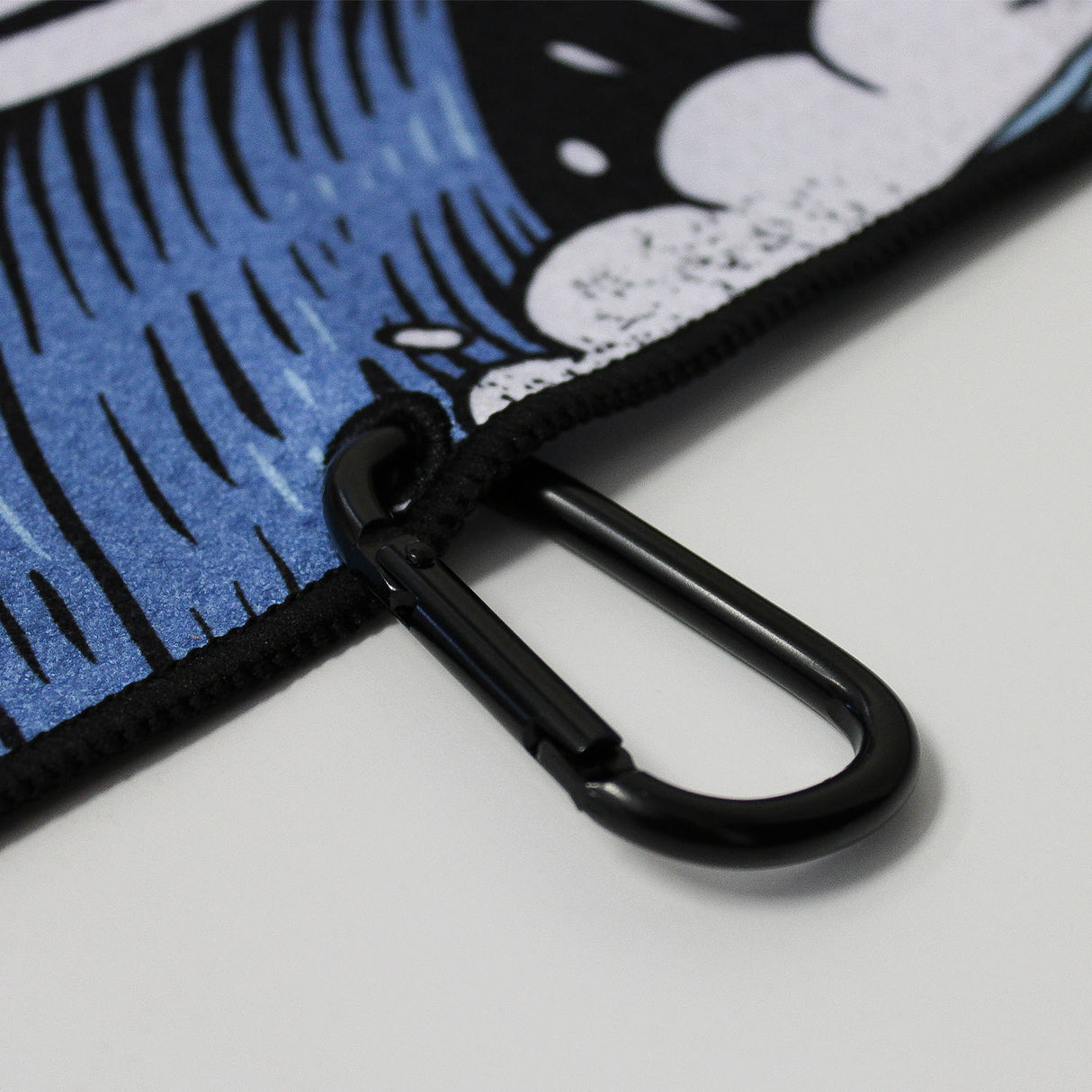 Close up of Utility Towel black carabiner clip with 'Own The Grind' graphic