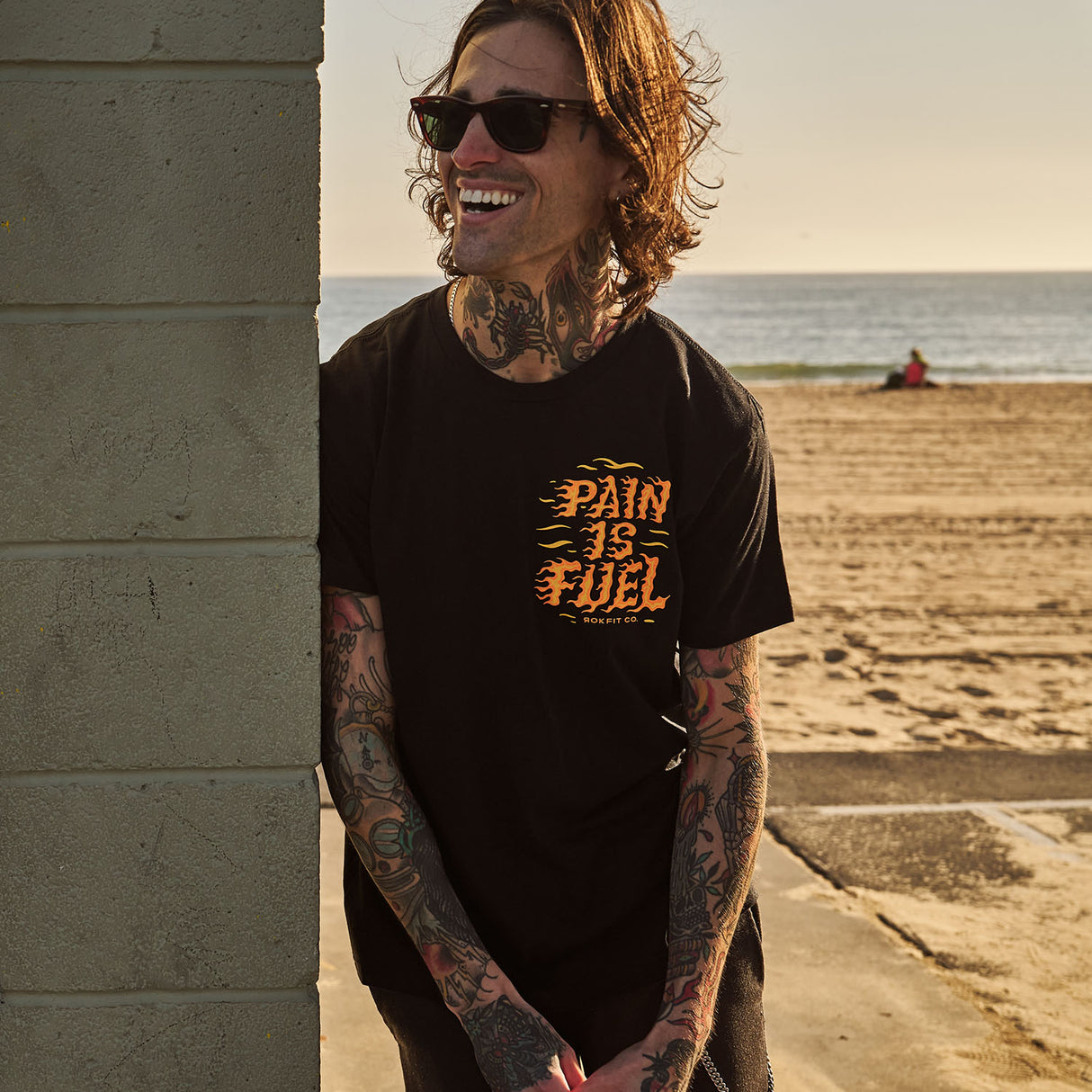 Male model outdoors wearing unisex Active Tee with 'Pain Is Fuel' graphic