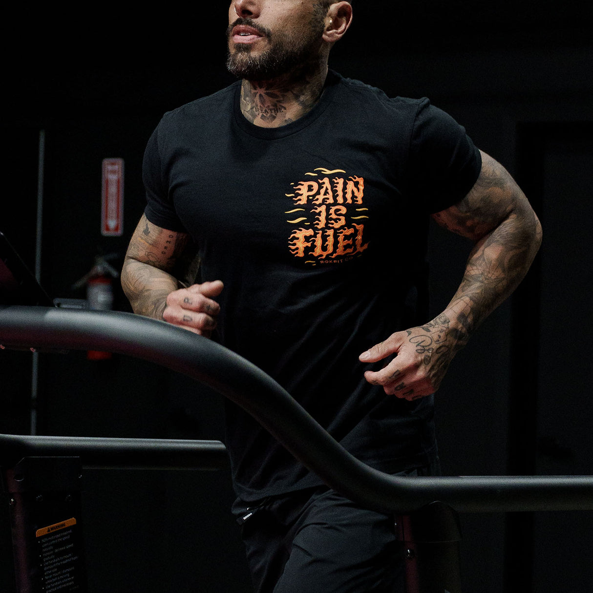 Male model running in a gym wearing Active Tee with 'Pain Is Fuel' graphic