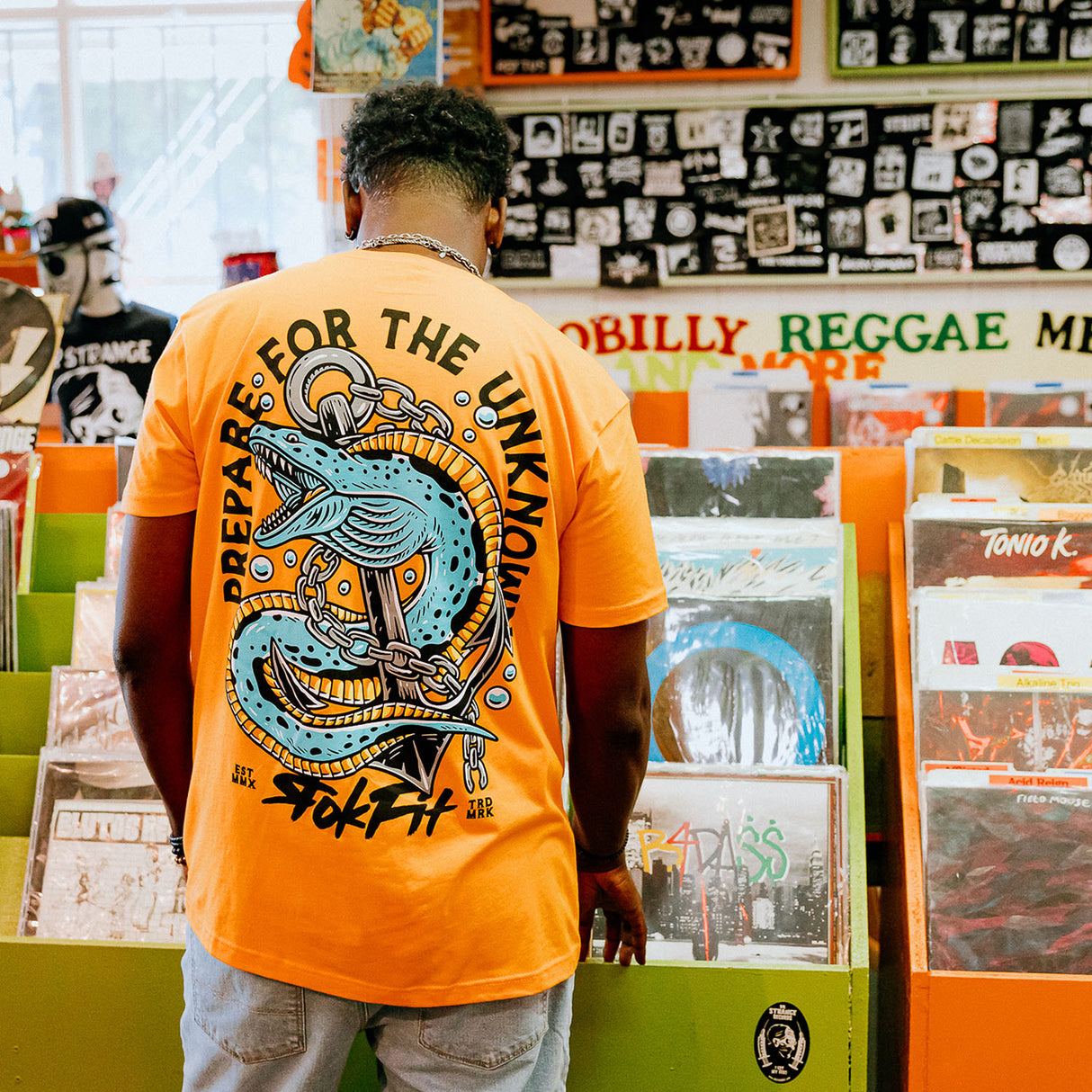 Male model in record store wearing unisex Active Tee with 'Prepare For The Unknown' graphic