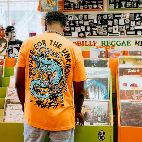 Male model in record store wearing unisex Active Tee with 'Prepare For The Unknown' graphic